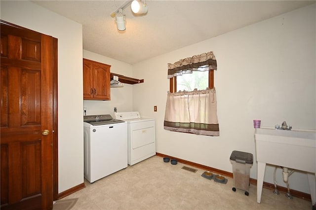 2406 NE 78th Ter, Kansas City, MO 64118 - laundry room with cabinet space, separate washer and dryer, baseboards, light flooring, and a textured ceiling