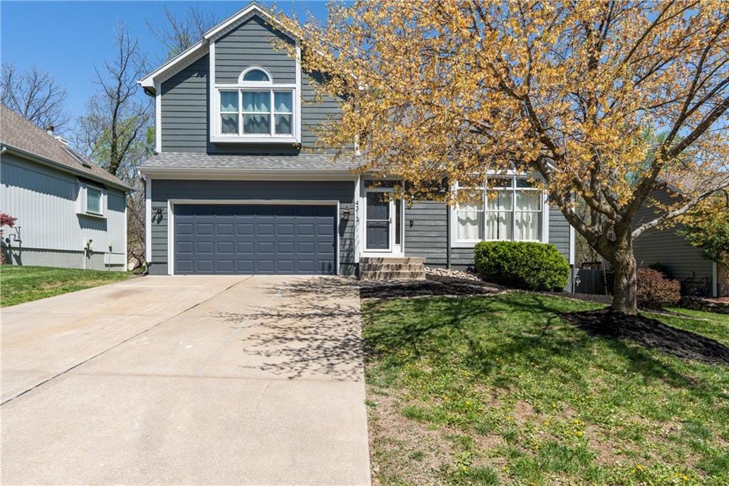 view of front of property featuring an attached garage, driveway, and a front lawn