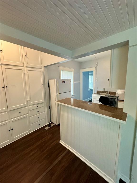 2518 N 12th St, Kansas City, KS 66104 - kitchen featuring white cabinetry, dark wood-style flooring, wooden ceiling, freestanding refrigerator, and a peninsula