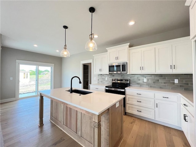16965 S Mahaffie St, Olathe, KS 66062 - kitchen with appliances with stainless steel finishes, a sink, tasteful backsplash, a center island with sink, and light countertops