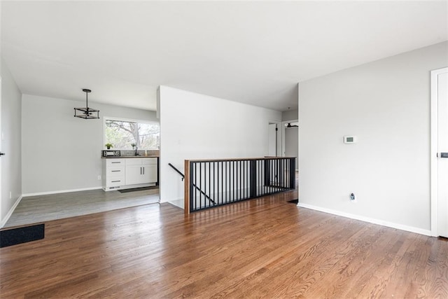 spare room with baseboards and wood finished floors
