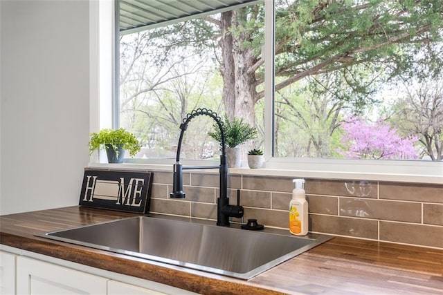 details with white cabinets, a sink, and tasteful backsplash