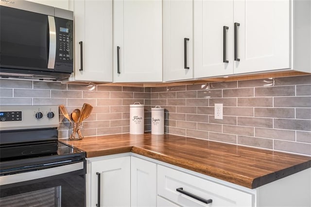 kitchen featuring butcher block countertops, decorative backsplash, white cabinetry, and appliances with stainless steel finishes