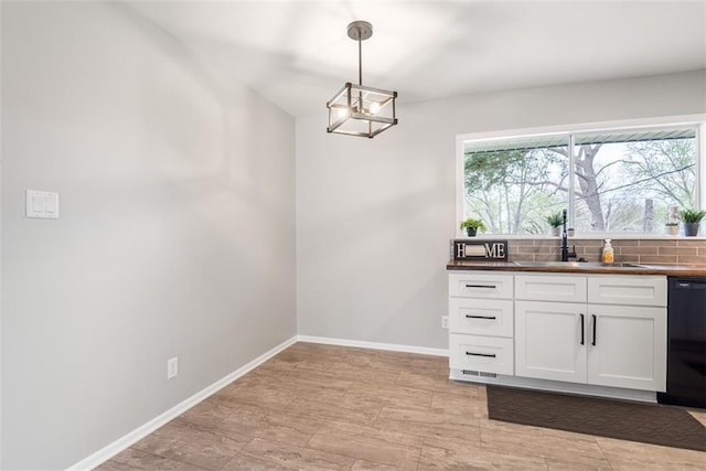 kitchen with dishwasher, a sink, dark countertops, and a wealth of natural light