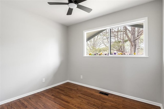 spare room featuring visible vents, dark wood-style floors, baseboards, and a wealth of natural light