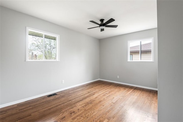 empty room featuring baseboards, visible vents, a ceiling fan, and wood finished floors
