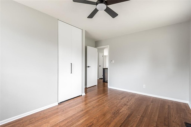 unfurnished bedroom featuring a closet, baseboards, ceiling fan, and wood finished floors