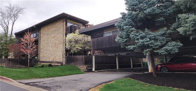 view of property exterior featuring stone siding and fence