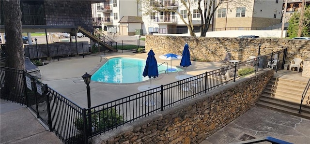 community pool featuring a patio area, stairway, and fence