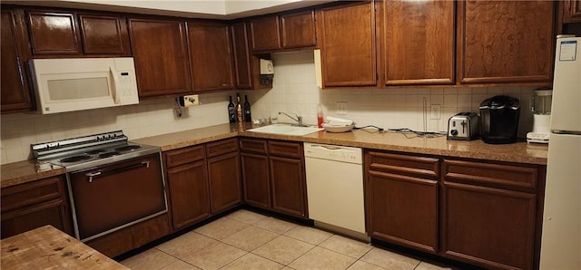 kitchen featuring a sink, white appliances, dark brown cabinetry, backsplash, and light tile patterned flooring