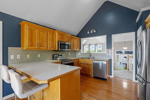 2357 SW Current Ct, Lees Summit, MO 64082 - kitchen featuring appliances with stainless steel finishes, a sink, light countertops, high vaulted ceiling, and a peninsula