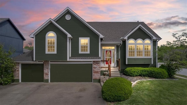 split level home with brick siding, a garage, a lawn, and driveway