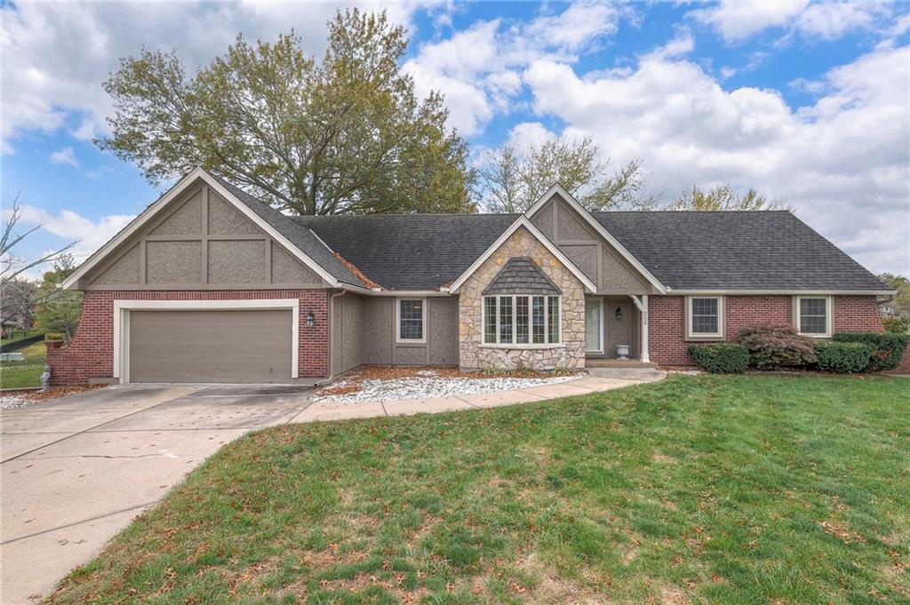 302 NW Bramble Trail Cir, Lees Summit, MO 64064 - view of front of house with concrete driveway, roof with shingles, an attached garage, stone siding, and a front yard