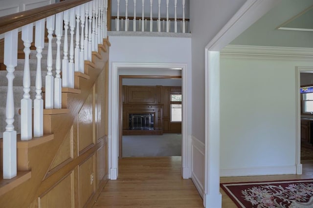 1313 NW 12th St, Blue Springs, MO 64015 - hall featuring wood finished floors, crown molding, stairway, and a decorative wall