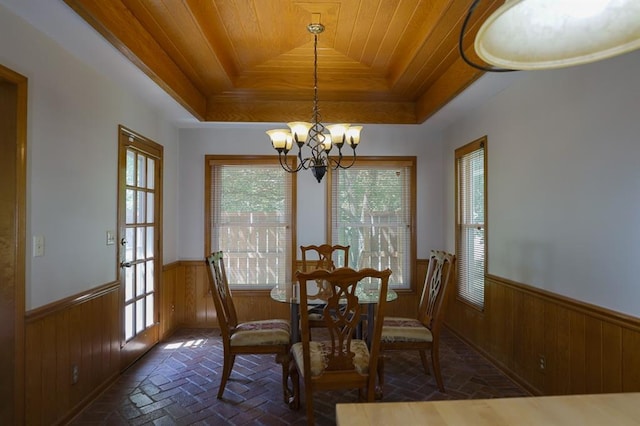 1313 NW 12th St, Blue Springs, MO 64015 - dining space with a raised ceiling, wood walls, a chandelier, a wainscoted wall, and brick flooring