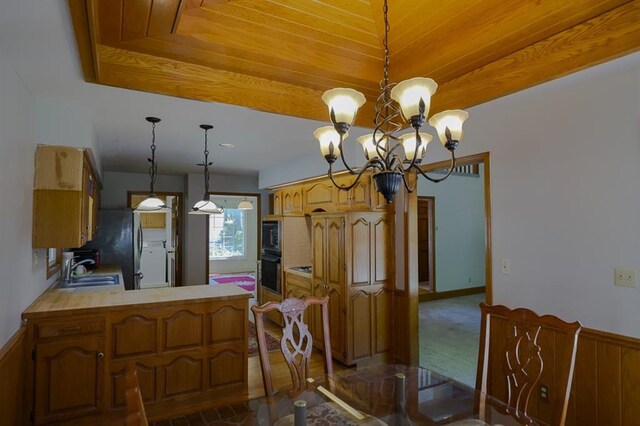 1313 NW 12th St, Blue Springs, MO 64015 - kitchen featuring a chandelier, a peninsula, light countertops, a sink, and brown cabinetry
