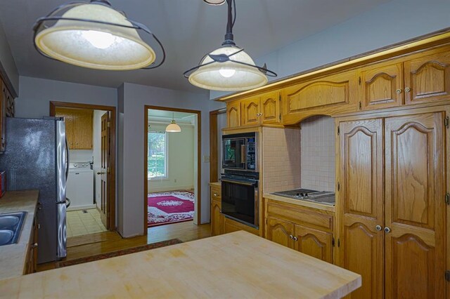 1313 NW 12th St, Blue Springs, MO 64015 - kitchen featuring black appliances, washer / dryer, tasteful backsplash, brown cabinets, and a sink