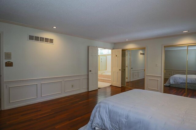 1313 NW 12th St, Blue Springs, MO 64015 - bedroom featuring two closets, wood finished floors, a decorative wall, a textured ceiling, and a wainscoted wall