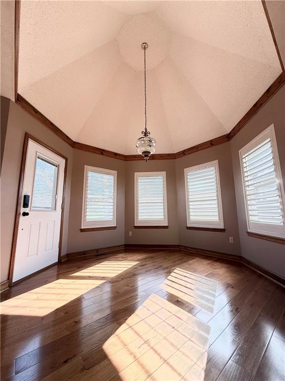 foyer featuring baseboards, hardwood / wood-style floors, and vaulted ceiling