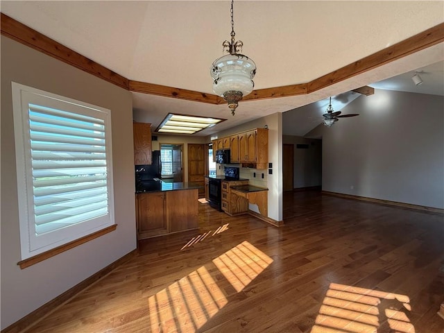 kitchen with vaulted ceiling with beams, dark countertops, dark wood finished floors, and black appliances