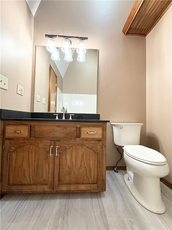bathroom with vanity, baseboards, toilet, and wood finished floors