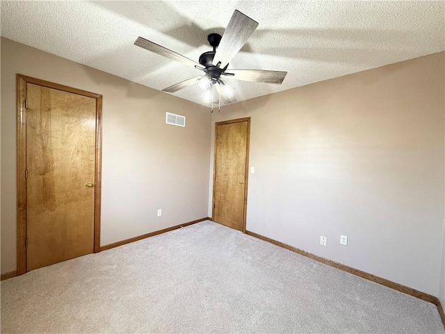 unfurnished bedroom with baseboards, carpet flooring, a textured ceiling, a ceiling fan, and visible vents