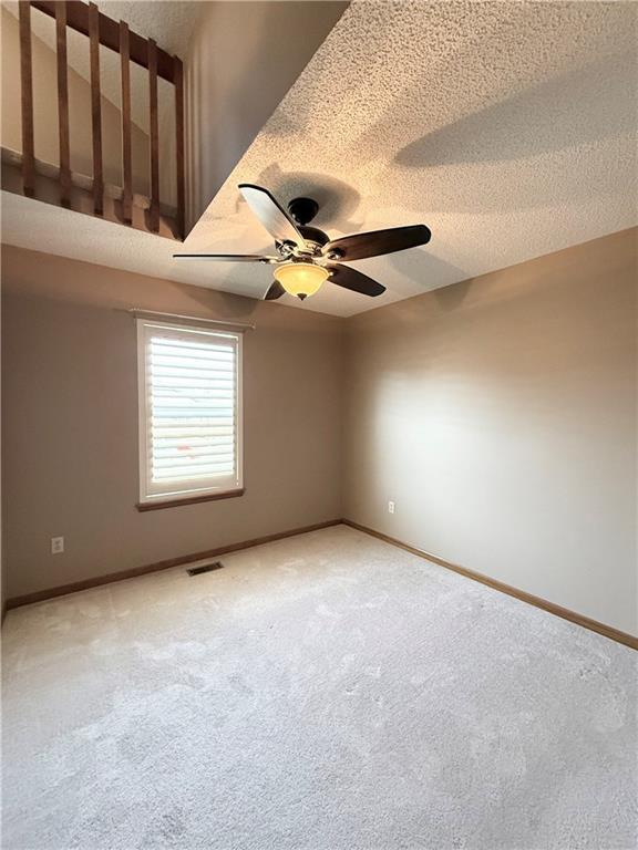 empty room featuring baseboards, visible vents, a textured ceiling, and a ceiling fan