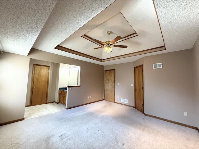 empty room featuring visible vents, a tray ceiling, and light carpet