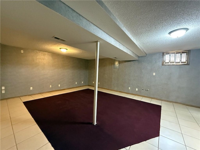 basement with tile patterned floors, visible vents, and a textured ceiling