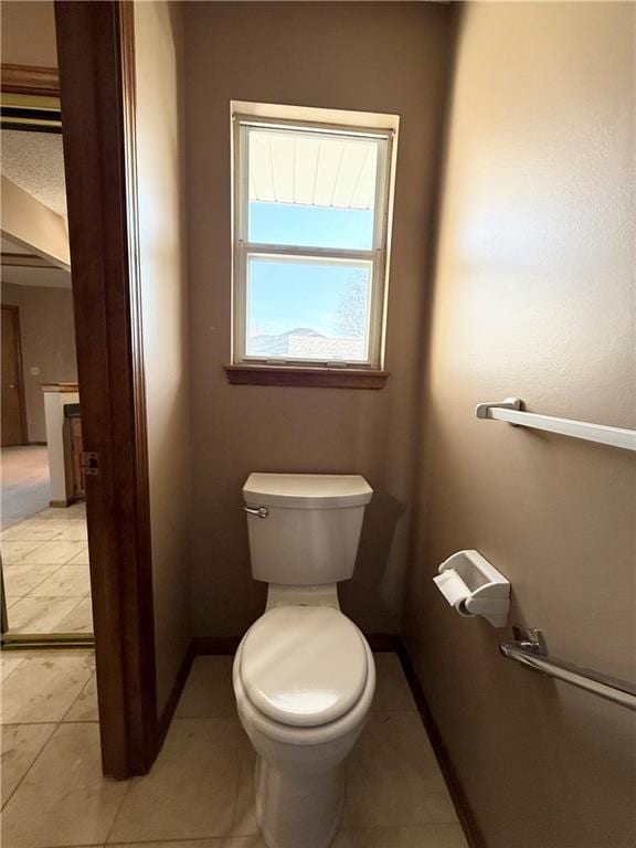 bathroom with tile patterned flooring, baseboards, and toilet