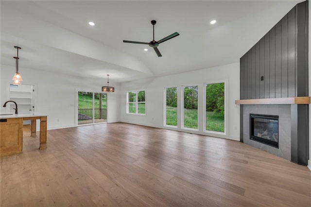 502 Seventh St, Smithville, MO 64089 - unfurnished living room with lofted ceiling, ceiling fan, light wood-style flooring, a large fireplace, and a sink