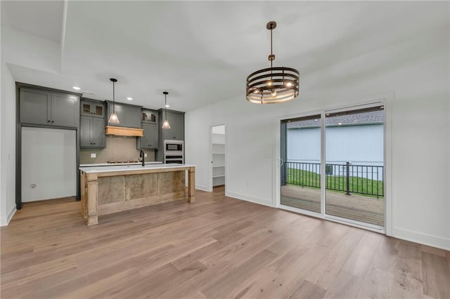 502 Seventh St, Smithville, MO 64089 - kitchen with stainless steel appliances, custom range hood, light countertops, light wood-style floors, and baseboards