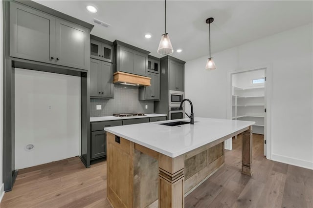 502 Seventh St, Smithville, MO 64089 - kitchen featuring a sink, stainless steel appliances, light wood finished floors, backsplash, and a center island with sink