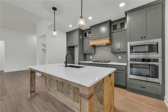 502 Seventh St, Smithville, MO 64089 - kitchen featuring stainless steel appliances, a sink, decorative backsplash, an island with sink, and light wood finished floors