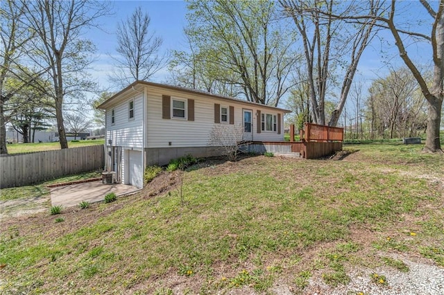 view of front of property featuring driveway, a front yard, a wooden deck, a garage, and fence