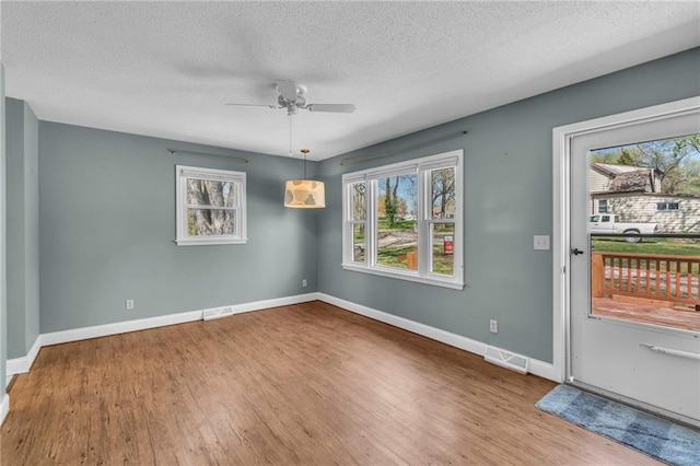 interior space with visible vents, baseboards, a ceiling fan, a textured ceiling, and wood finished floors