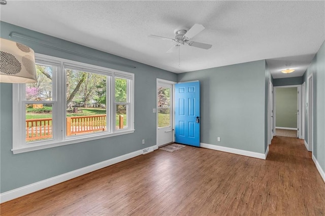 spare room with baseboards, a textured ceiling, visible vents, ceiling fan, and wood finished floors