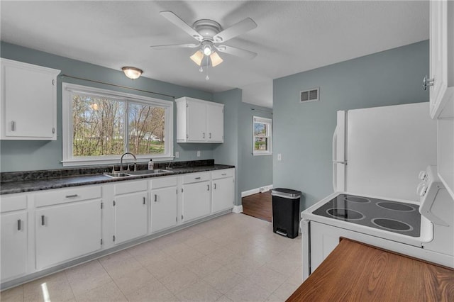 kitchen with white appliances, a ceiling fan, white cabinets, visible vents, and a sink