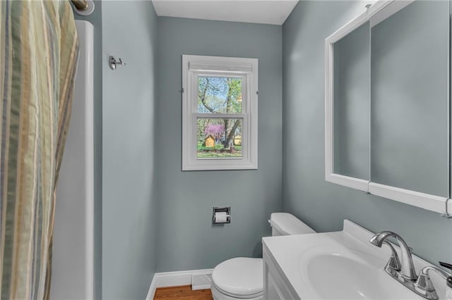 bathroom with baseboards, a sink, toilet, and wood finished floors