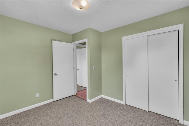 unfurnished bedroom with a textured ceiling, a closet, carpet flooring, and baseboards