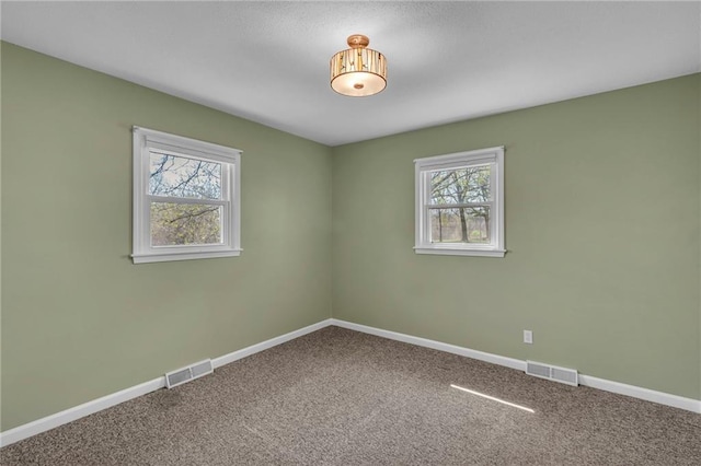 empty room with visible vents, baseboards, and carpet floors