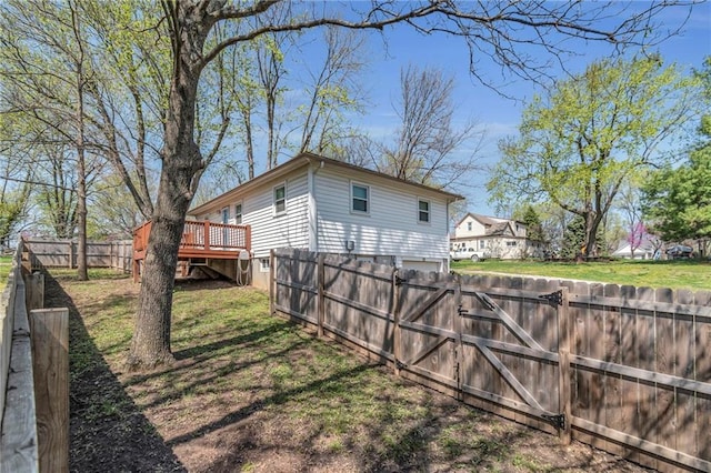 exterior space featuring a wooden deck, a garage, fence, and a gate
