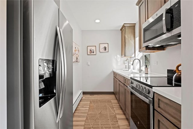 33345 W 95th St, De Soto, KS 66018 - kitchen with appliances with stainless steel finishes, a baseboard heating unit, a sink, light wood-style flooring, and light countertops
