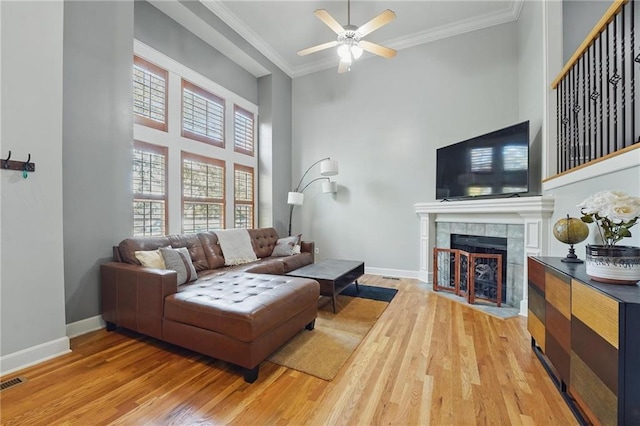 living room featuring baseboards, a fireplace, a ceiling fan, and light wood-type flooring