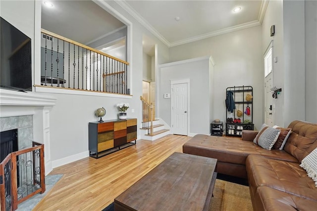 living room with crown molding, a fireplace, wood finished floors, stairway, and baseboards
