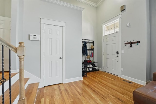 entrance foyer featuring visible vents, ornamental molding, stairway, and light wood-type flooring