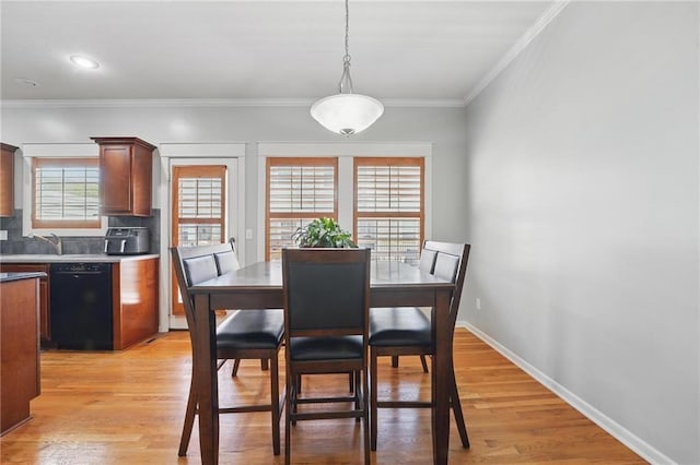 dining space with crown molding, baseboards, and light wood-style flooring