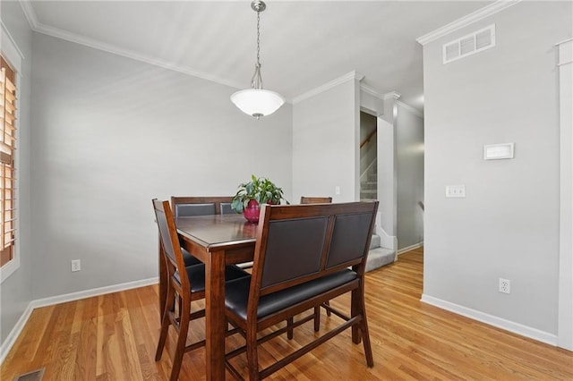 dining space with crown molding, baseboards, visible vents, and light wood-style flooring