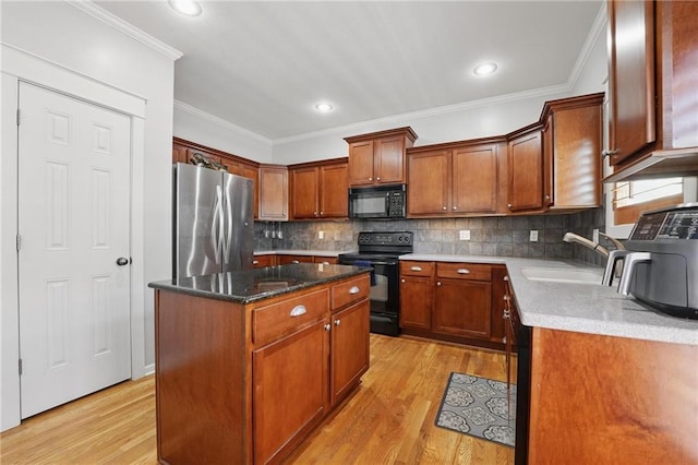kitchen with a sink, ornamental molding, black appliances, and light wood-style flooring