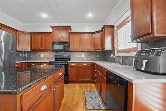 kitchen featuring crown molding, a sink, light wood finished floors, and black appliances